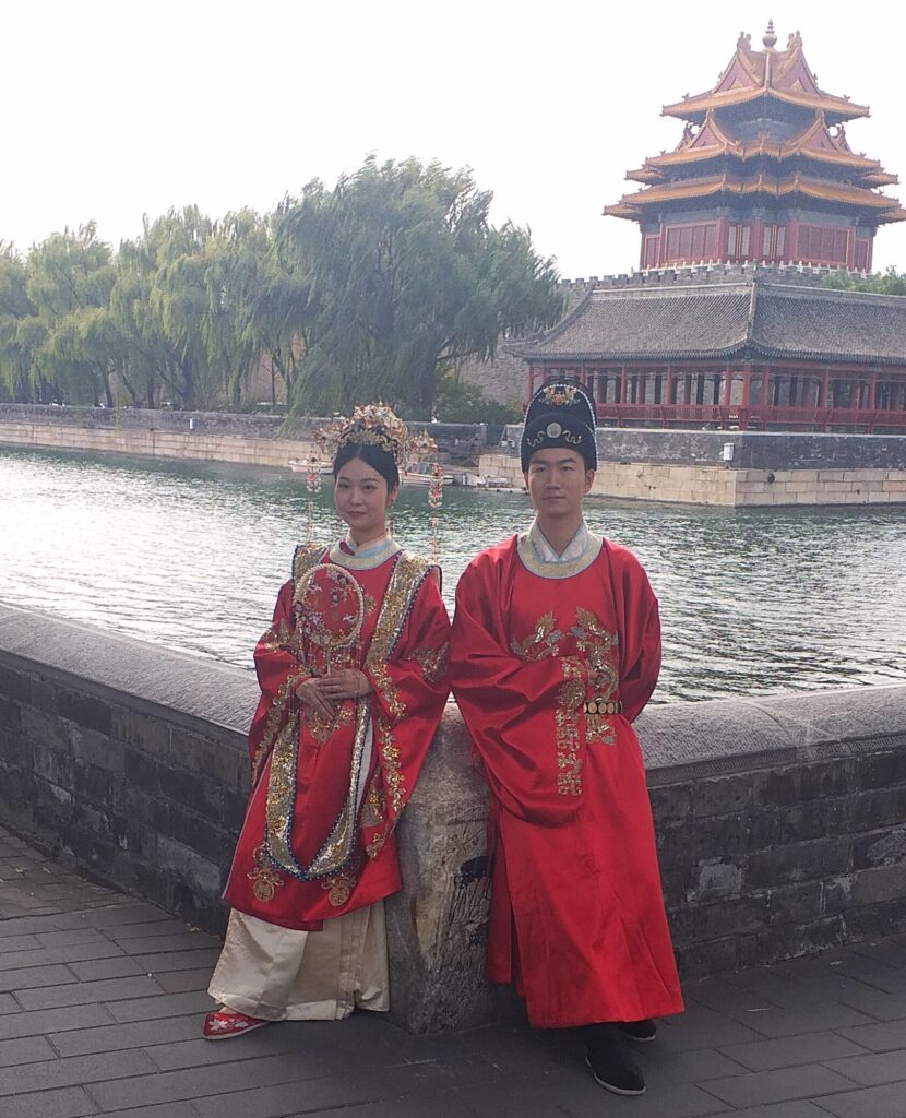 Pechino, ottobre 2023. Una coppia di sposi in abito tradizionale accanto al fossato della città proibita 
